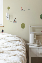 Children's room with wallpaper pattern of a boy on a bike, a girl, and trees.
