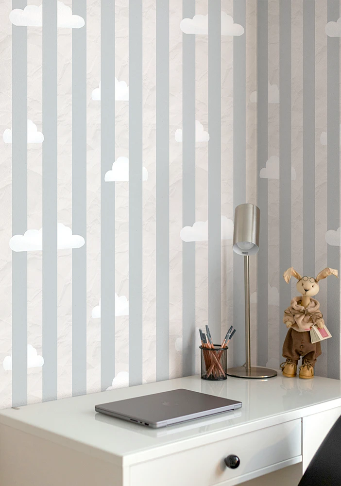 Teenage room with a wallpaper with cloud patterns. a desk with laptop, pen holder, and decorative items.