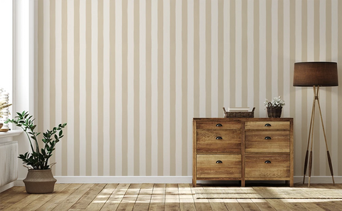 Wooden dresser with decorative items against a wall with a beige striped wallpaper pattern.