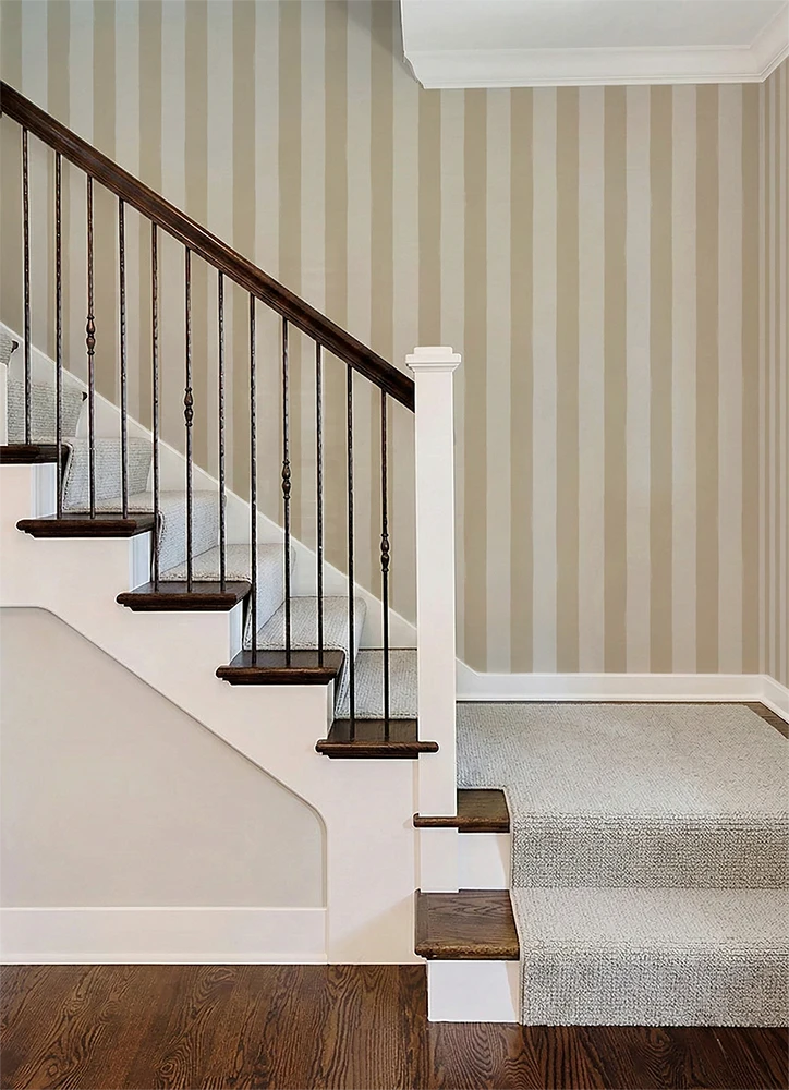 Staircase with wooden steps and metal railing against a wall with a beige striped wallpaper pattern.