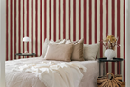 Bedroom with red and white striped wallpaper, bed with beige pillows, and side tables.