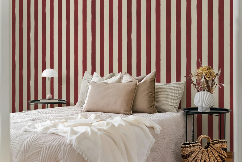 Bedroom with red and white striped wallpaper, bed with beige pillows, and side tables.