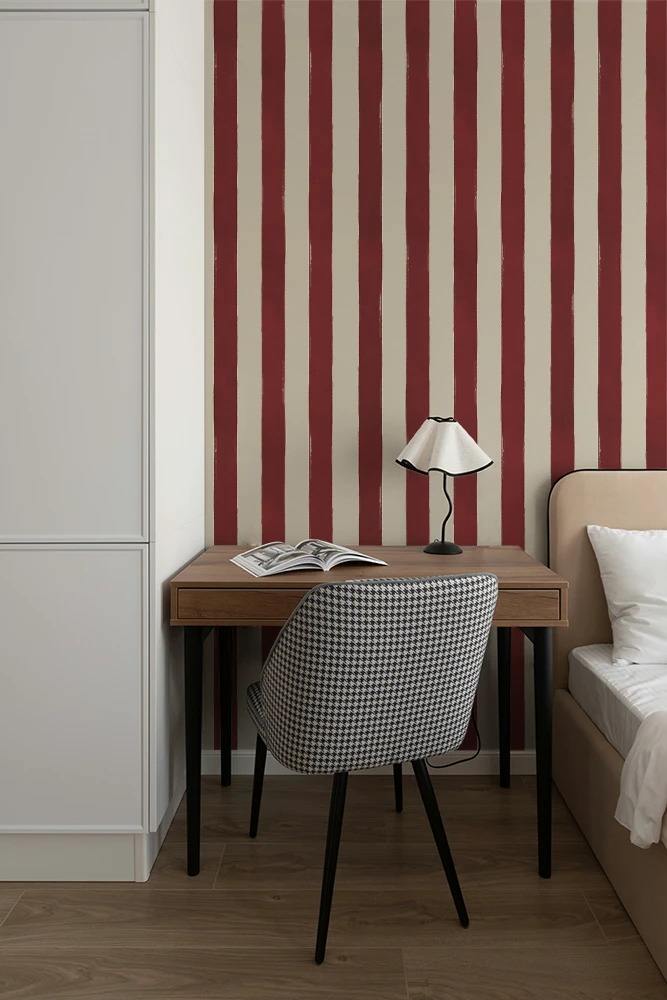 Small desk with lamp and chair against a red and white striped wallpaper.