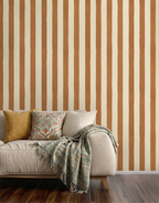 Beige sofa with decorative pillows and a blanket against a striped caramel wallpaper.