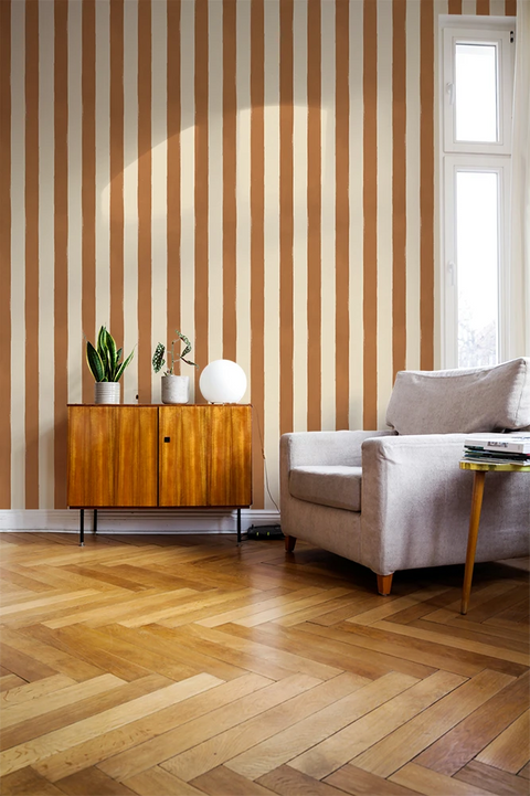 Living room with striped wallpaper, wooden floor, and furniture.