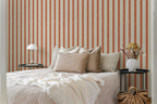Bedroom with striped orange wallpaper, bed with pillows, and side tables.