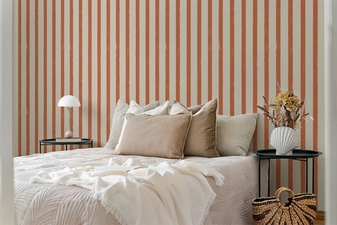 Bedroom with striped orange wallpaper, bed with pillows, and side tables.