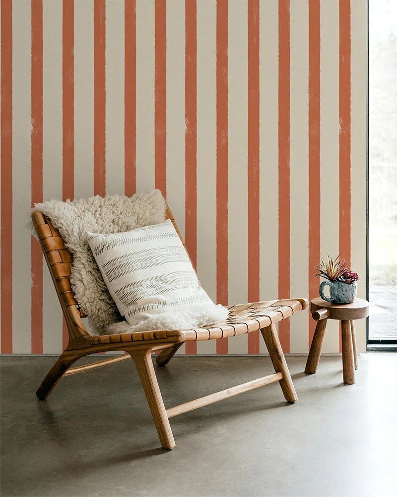Wooden chair with cushions against a striped orange wallpaper