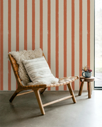 Wooden chair with cushions against a striped orange wallpaper