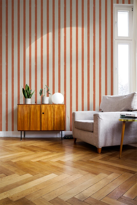 Living room with orange striped wallpaper, wooden floor, and furniture.