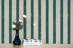 Stack of books with a vase and flowers against a striped wallpaper background
