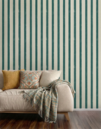 Sofa with decorative pillows and a blanket against a wall with blue striped wallpaper.