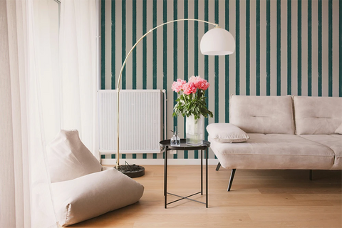 Modern living room with a gray sofa, striped wallpaper, and a floor lamp.