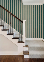 Staircase with wooden railings and striped green and white wallpaper.
