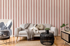 Modern living room with a grey sofa with a dog sitting in the middle, a grey blanket, black sofa table, and a striped wallpaper with pink brush strokes. 