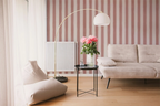 Modern living room with a beige sofa,  a lamp, and a striped wallpaper with pink brush strokes. 