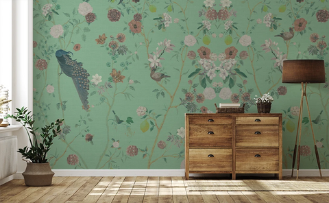 Floral chinoiserie wallpaper with peacocks and flowers, a wooden side table, and a lamp. 