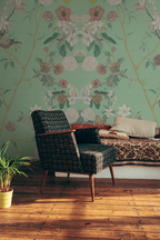 Floral chinoiserie wallpaper in a retro lounge with an arm chair. 