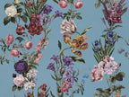 A vintage botanical pattern featuring an assortment of flowers including pink roses, purple irises, yellow tulips, and white blossoms on a dusty blue background.