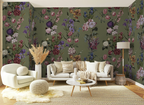 A styled living room featuring olive green floral wallpaper as the main product, shown behind a white sofa, armchair, coffee table, rug, and floor lamp.