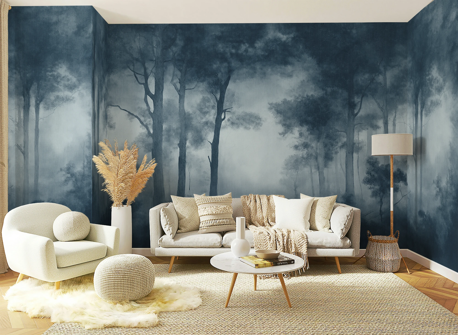 A styled living room featuring a large forest mural wallpaper on the back wall, with a cream sofa, matching armchair, round ottoman, coffee table, and a floor lamp.