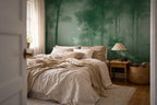 A styled bedroom interior featuring a forest mural wallpaper on the back wall, dressed with beige and cream bedding, a wooden nightstand with a lamp, and a woven basket.