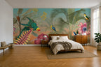 A tropical jungle-themed wallpaper mural displayed on the main wall of a modern bedroom. The mural features colorful parrots, green palm leaves, pink flowers, and a turquoise sky background.