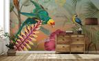 A tropical jungle wallpaper mural featuring a green parrot, a blue-and-yellow macaw, and large palm leaves, shown installed on a wall in a styled room with a wooden dresser, floor lamp, and potted plant.