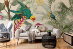 A styled living room featuring a large-scale tropical wallpaper mural with parrots and palm leaves. A light gray sofa sits in the center with a dog lying on it, alongside a black woven side table, a small side table with a mirror, and a vintage-style cabinet.