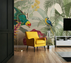 A styled living room featuring a bold tropical wallpaper with parrots and palm leaves, a bright yellow armchair, a gold floor lamp, and a white side table.