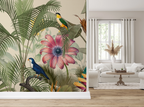 Tropical jungle wallpaper mural featuring a large pink passion flower, green palm leaves, and two colorful birds (one blue, one yellow/green) shown installed in a bright, modern living room with a white sofa and window.