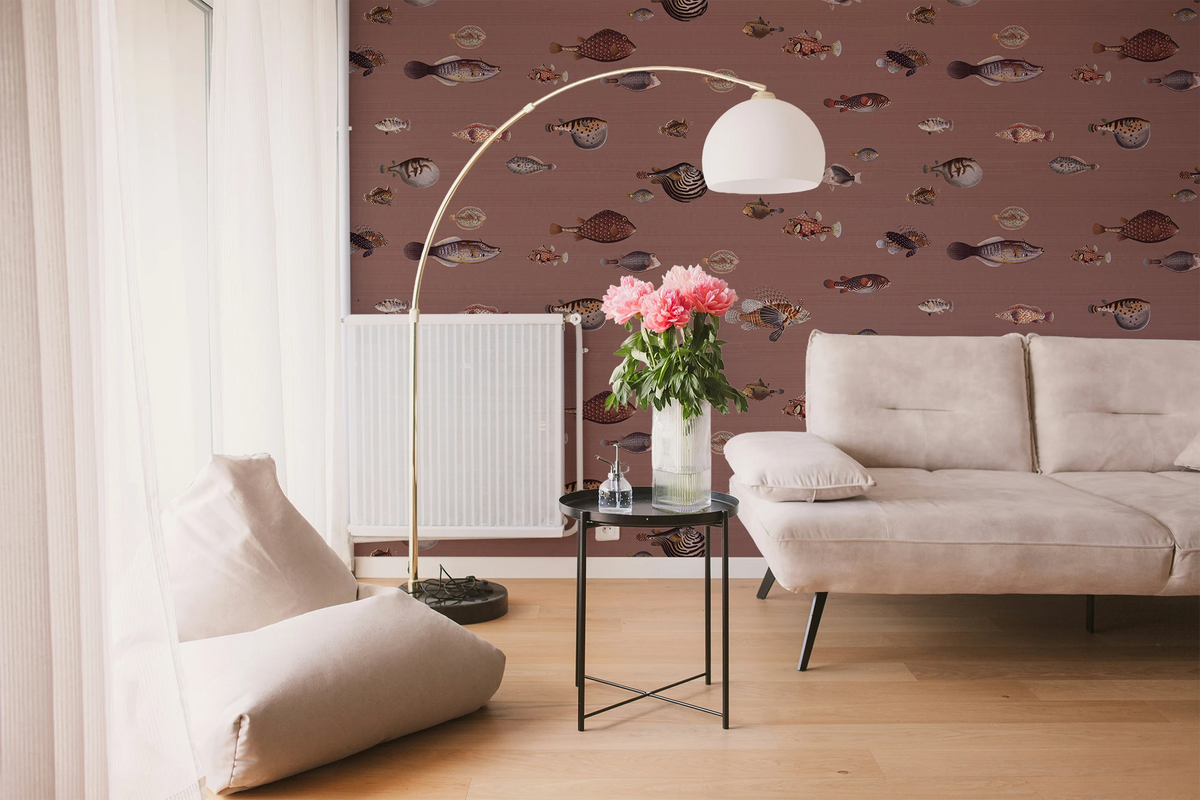 A modern living room with a white sofa, a vase, a floor lamp, and a wallpaper with a brown background featuring a pattern of vintage marine life illustrations. 