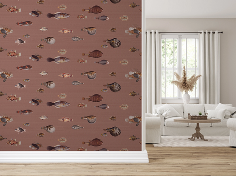 A styled interior room showing a large wall covered in fish-patterned wallpaper on the left made with vintage hand drawn illustrations, with a white sofa, window, curtains, and wood floor visible on the right.