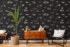 Mid century lounge living room, with a wooden side table, books, a black chair, and a plant with a textile pot. The wall features a wallpaper with a black background featuring a pattern of vintage marine life illustrations. 