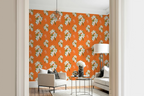 Bright living room interior featuring a bold Hermes orange wallpaper with a repeating white floral pattern, styled with light beige armchair, sofa, glass side table, and white floor lamp.