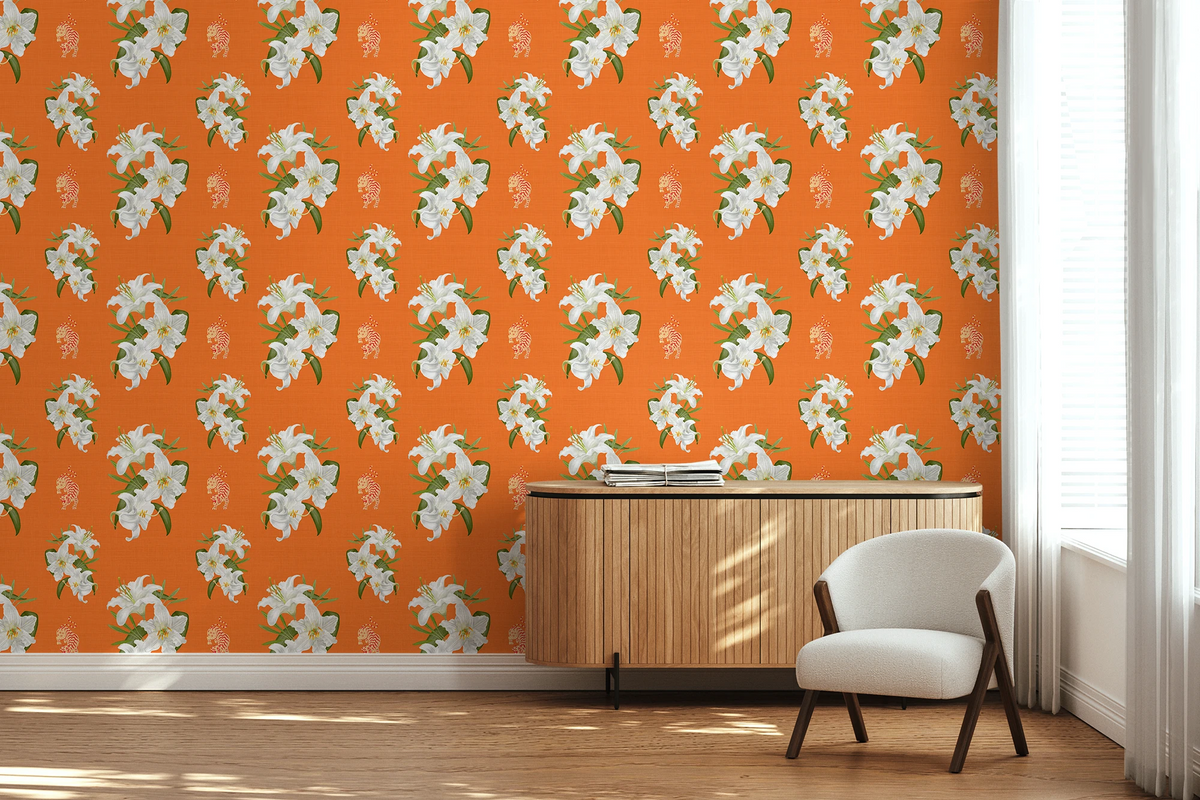Bright room corner with bright Hermes orange wallpaper featuring a repeating white floral pattern with orange tigers, a light wood sideboard, and a white upholstered chair near a window.