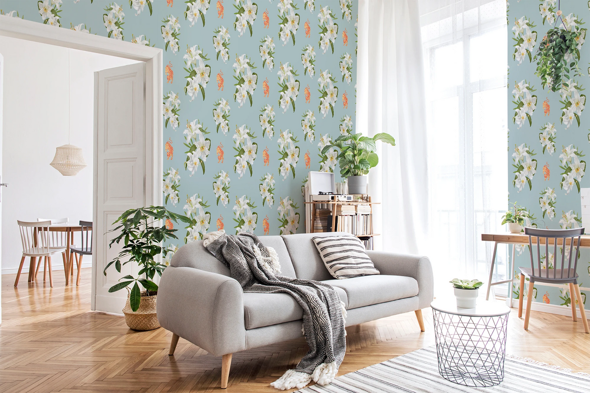 A styled living room featuring Tiffany blue wallpaper with a white floral pattern  with orange tigers, a light gray sofa with a gray throw blanket, wooden flooring, and various home decor elements.