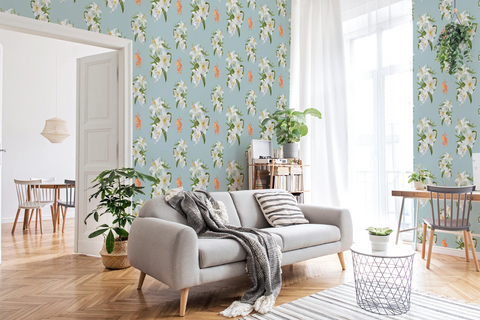 A styled living room featuring Tiffany blue wallpaper with a white floral pattern  with orange tigers, a light gray sofa with a gray throw blanket, wooden flooring, and various home decor elements.