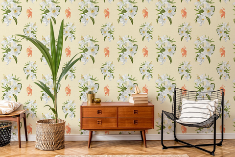 A styled interior room featuring wallpaper with a repeating pattern of white flowers, green leaves, and small orange tigers on a pale yellow background. A mid-century wooden sideboard, a black wire chair with a striped pillow, a tall potted plant, and a small table are arranged in front of the wall.