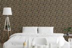 A modern bedroom with white linens, a wooden nightstand, and the wall features a tapestry wallpaper with an oak leaf pattern. 