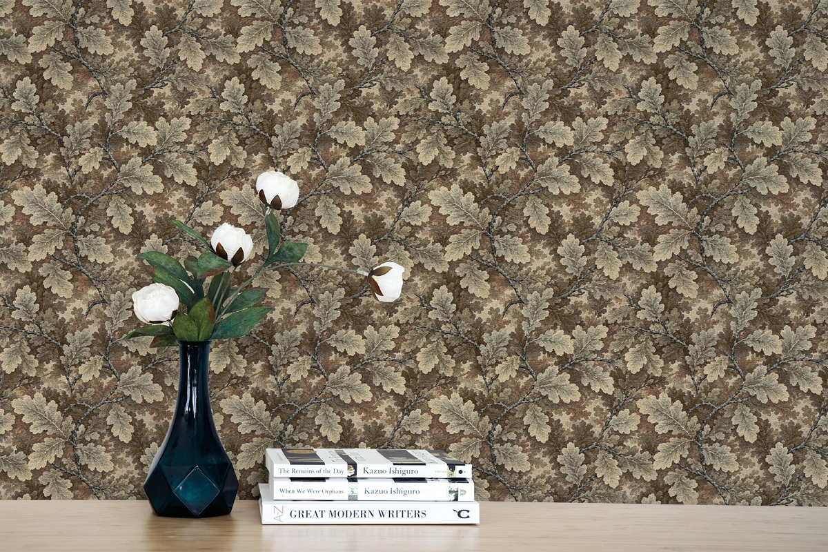 A console table with books, a vase, and a wall featuring a tapestry wallpaper in an oak leaf pattern. 