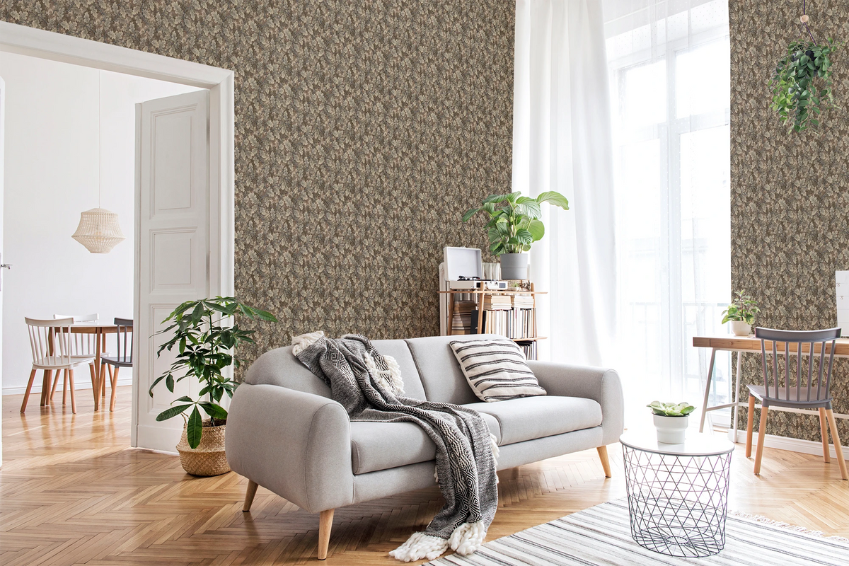 A modern living room with a grey sofa, green plants, and a wall featuring a tapestry wallpaper in an oak leaf pattern. 