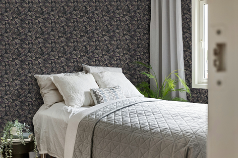 Modern bedroom with a grey and white bedcover, a plant, and a wall with a tapestry wallpaper featuring a dark oak leaf pattern. 