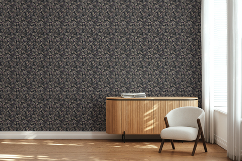 A modern lounge with a white textile chair, a wooden side board, and a tapestry wallpaper featuring a dark oak leaf pattern. 