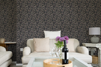 Modern living room with a white sofa, a glass sofa table, and a wall with a tapestry wallpaper featuring a dark oak leaf pattern. 