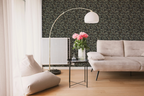 Modern living room with a white sofa, a glass sofa table, and a wall with a tapestry wallpaper featuring a green oak leaf pattern. 