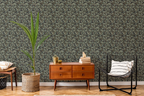Modern living room with a wooden sideboard, a lounge chair, a plant, sofa, and a tapestry wallpaper featuring a green oak leaf pattern. 