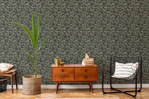Modern living room with a wooden sideboard, a lounge chair, a plant, sofa, and a tapestry wallpaper featuring a green oak leaf pattern. 
