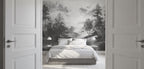 Modern bedroom with white sheets, opened white doors, and a black and white wallpaper mural of a forest landscape. 