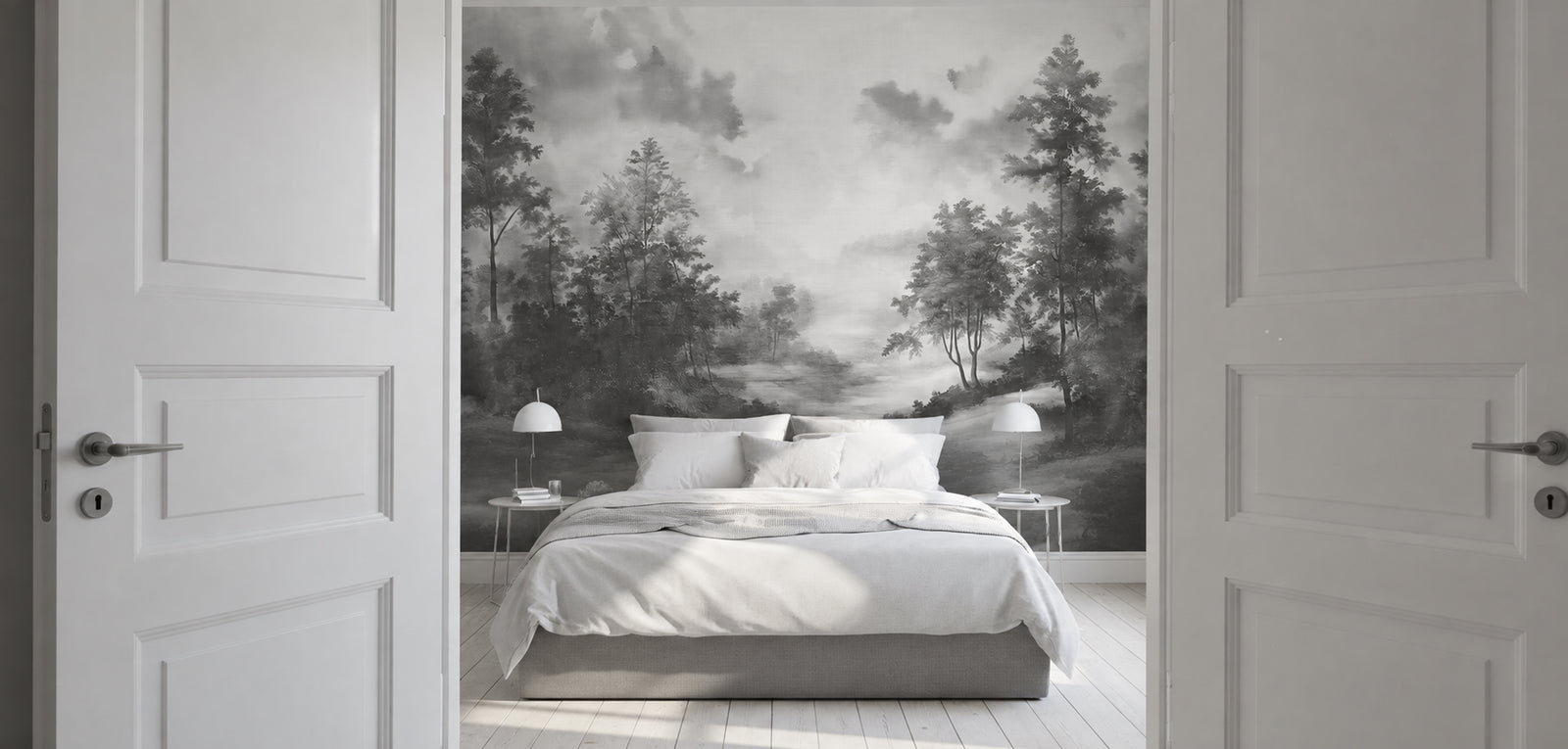 Modern bedroom with white sheets, opened white doors, and a black and white wallpaper mural of a forest landscape. 